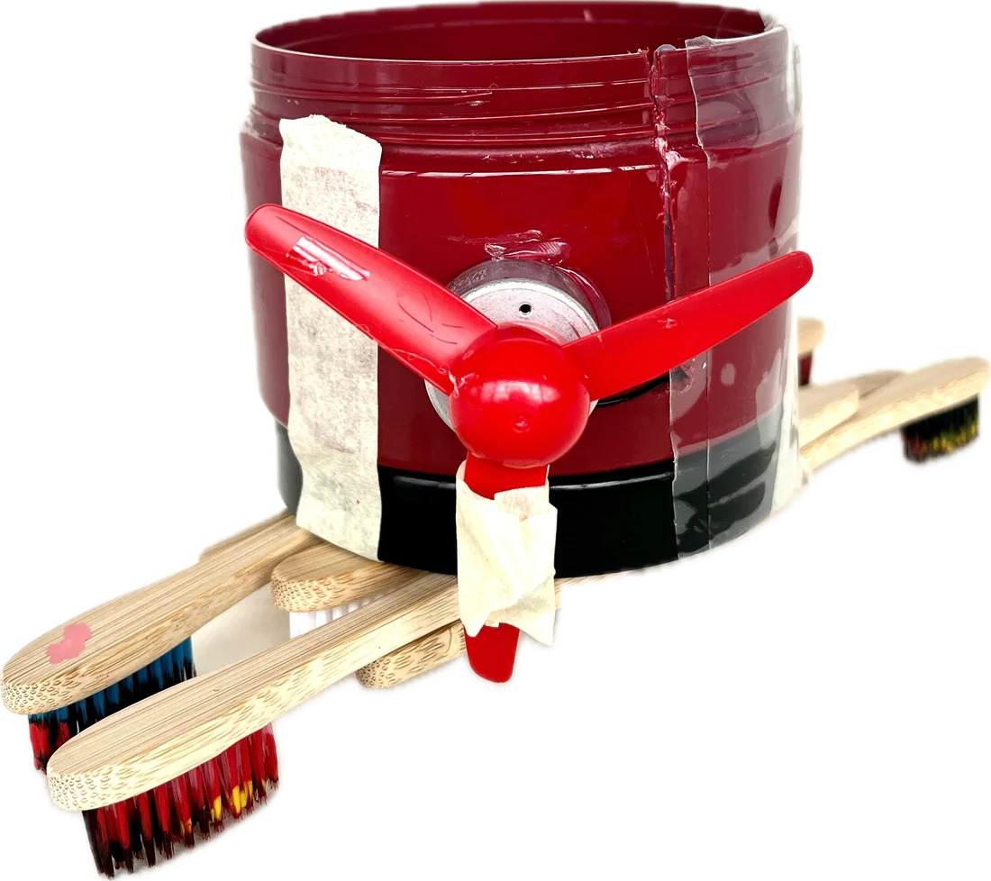 Robot 2: red jar with fan, standing on painted bamboo toothbrushes