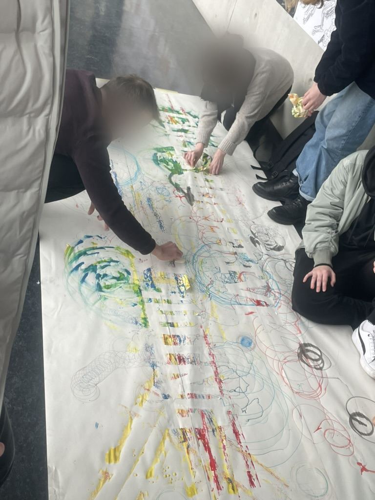 Students kneeling around the long paper covered in robot traces