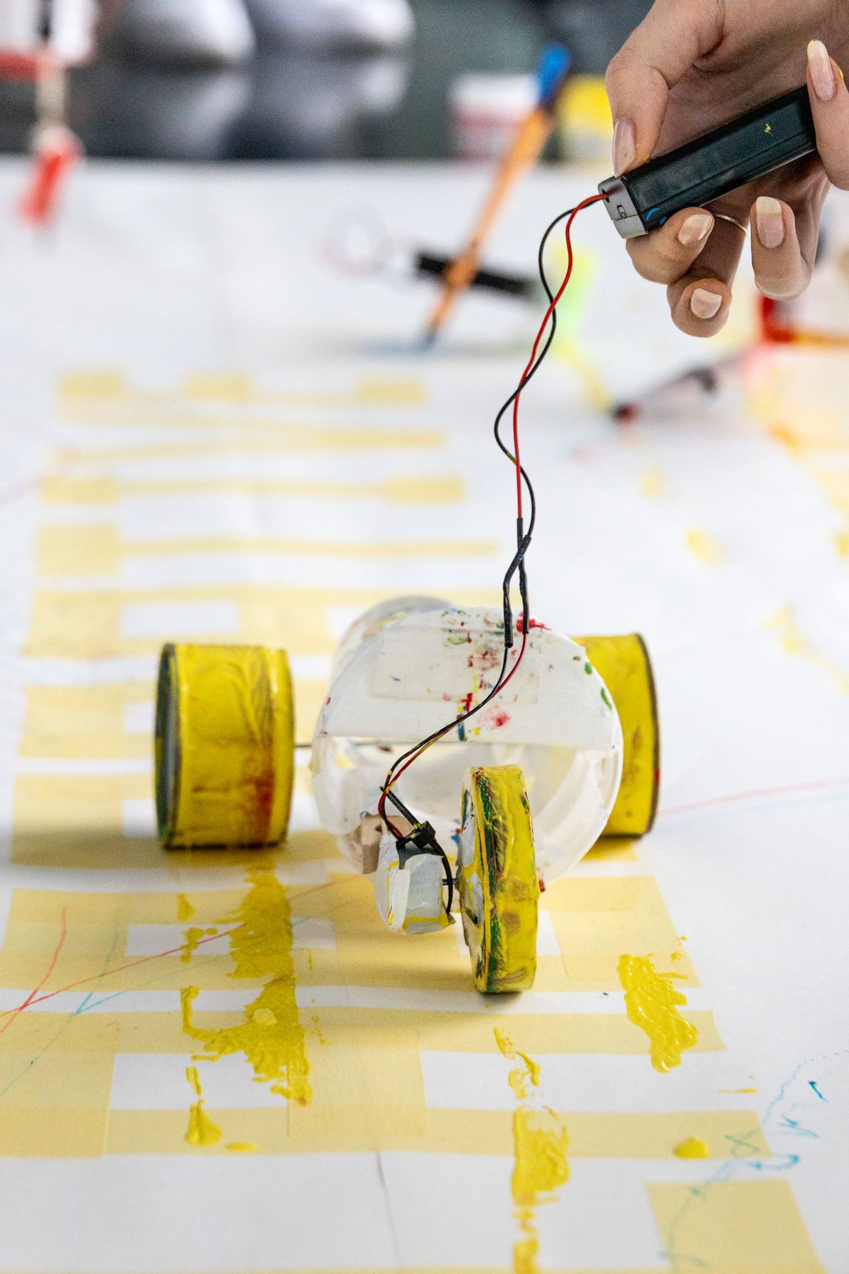 A cup robot on yellow wheels connected to a battery pack
