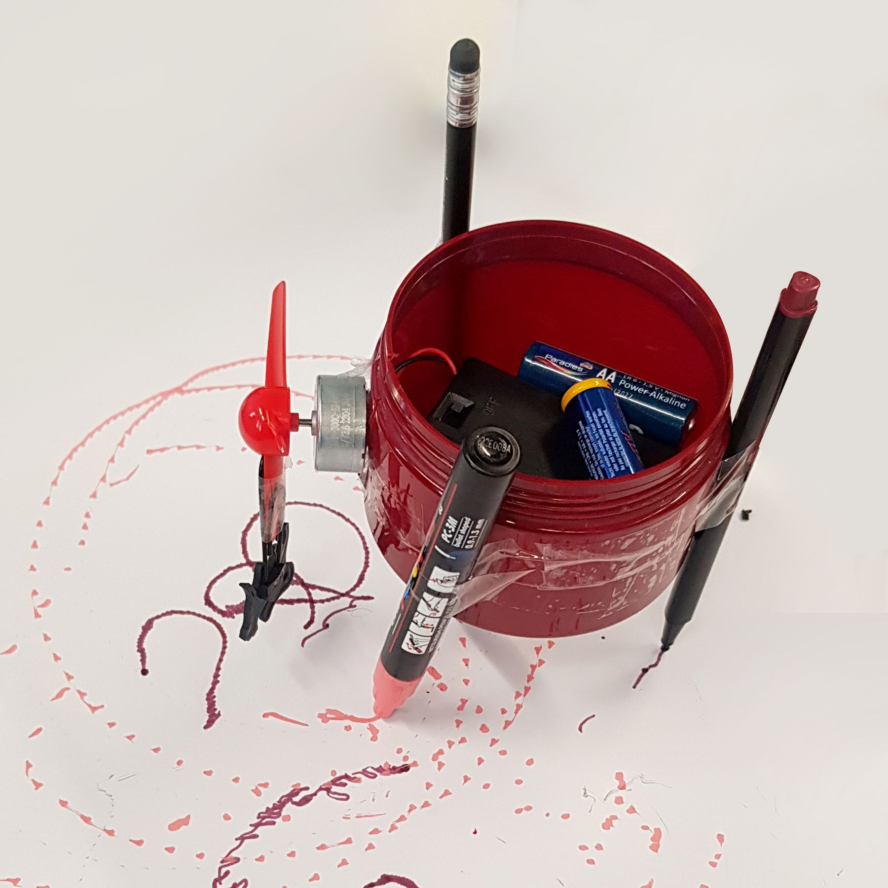 Robot 1 standing on paper surrounded by dotted pink and dark red lines