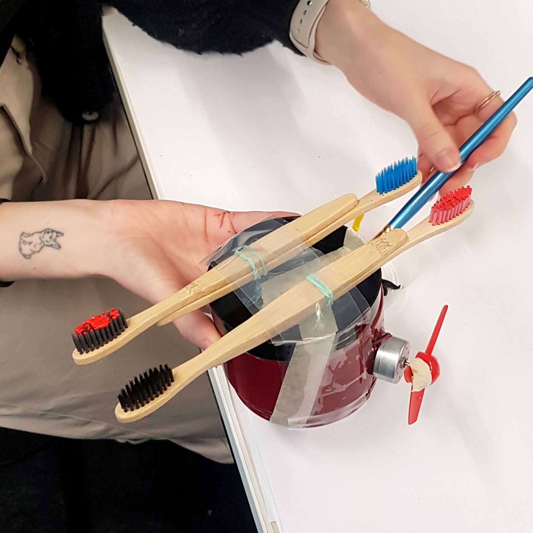 Hands holding the jar with bamboo toothbrushes taped across it