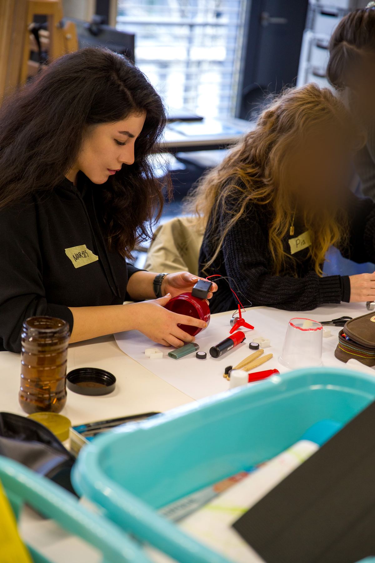 Narsis Dibaj fixing a fan motor to a red jar; her teammate works next to her