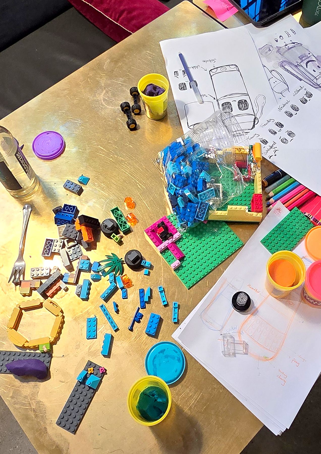 Work table with bottle sketches, LEGO bricks and modelling clay
