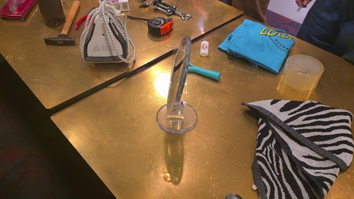Objects on the table: mirror, iron, hammer, tape measure, towel, T-shirt