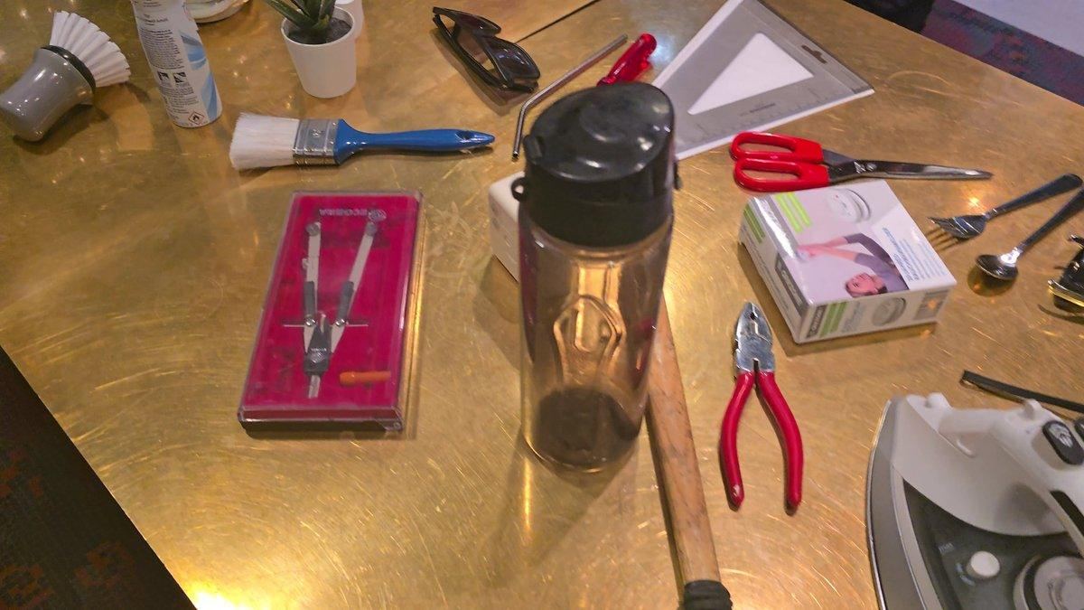 Objects on the table: the dark drinking bottle, compass set, pliers, scissors