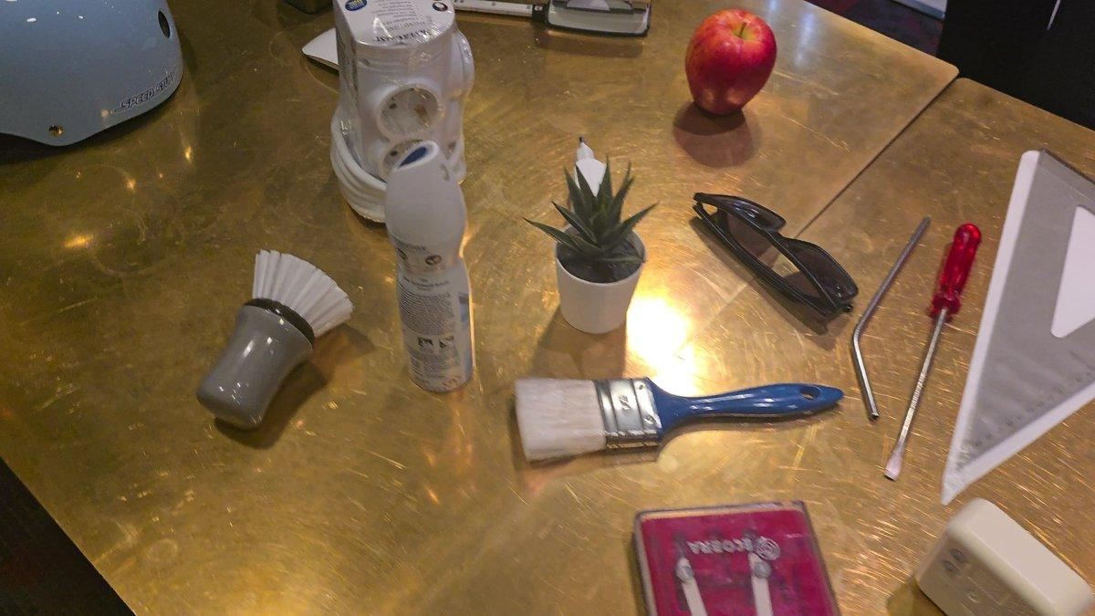 Objects on the table: bike helmet, spray can, plant, paintbrush